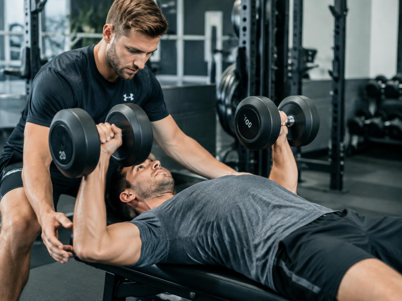 Coach spotting a dumbbell bench press for a Rancho Mission Viejo muscle-building client